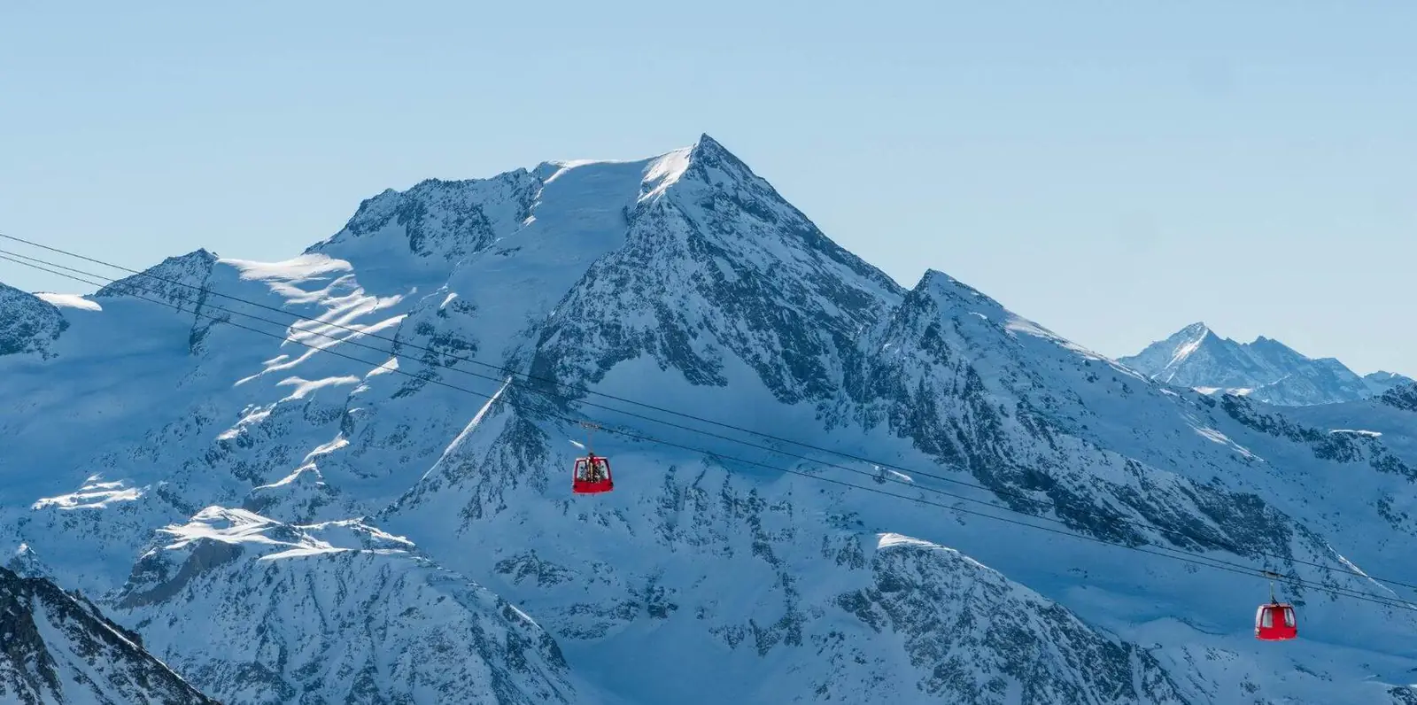 Red gondolas crossing in front of snowy peaks at La Plagne, Paradiski