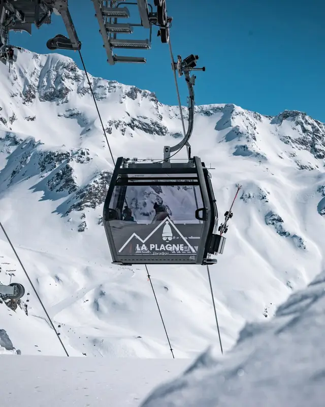 La Plagne Paradiski gondola above snowy peaks under a blue sky