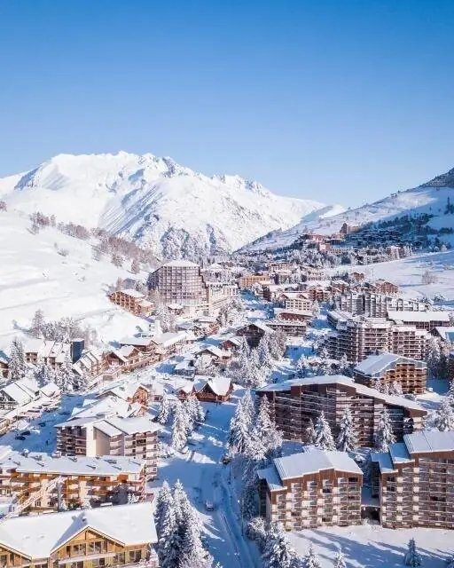 Les 2 Alpes village and ski slopes under fresh snow and blue sky