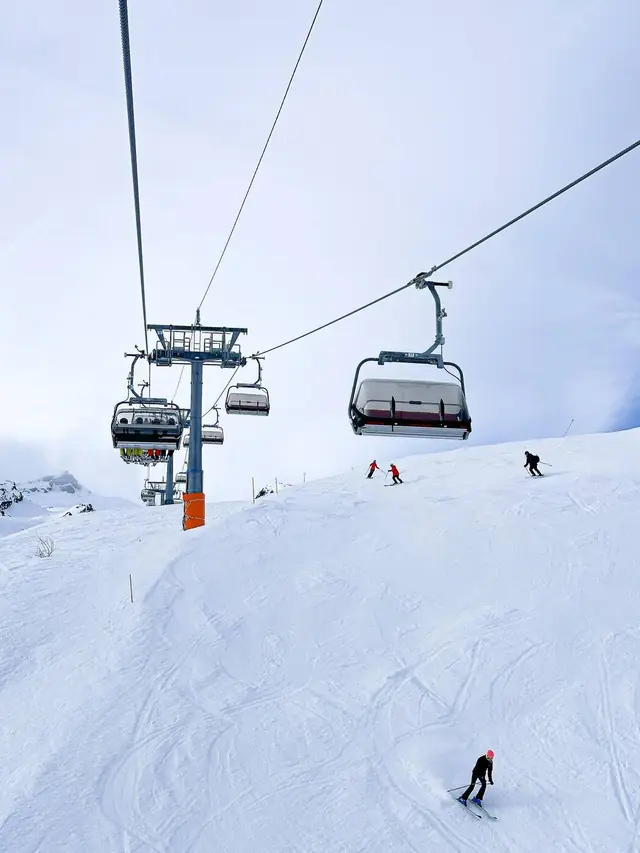 Skiers on a groomed piste under a chairlift in Les Arcs, Paradiski
