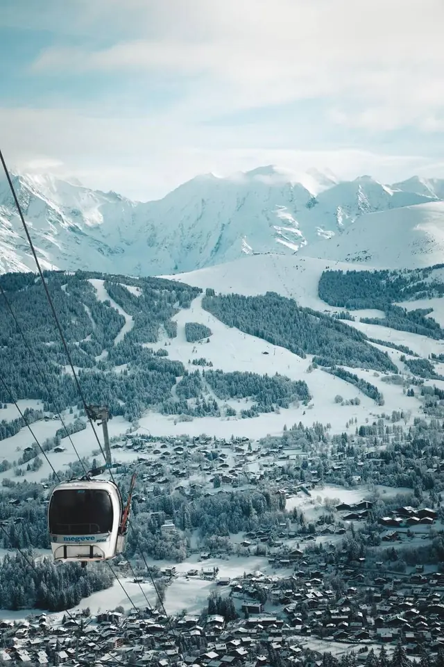 Megève gondola above the snowy village and ski pistes, Mont Blanc massif beyond