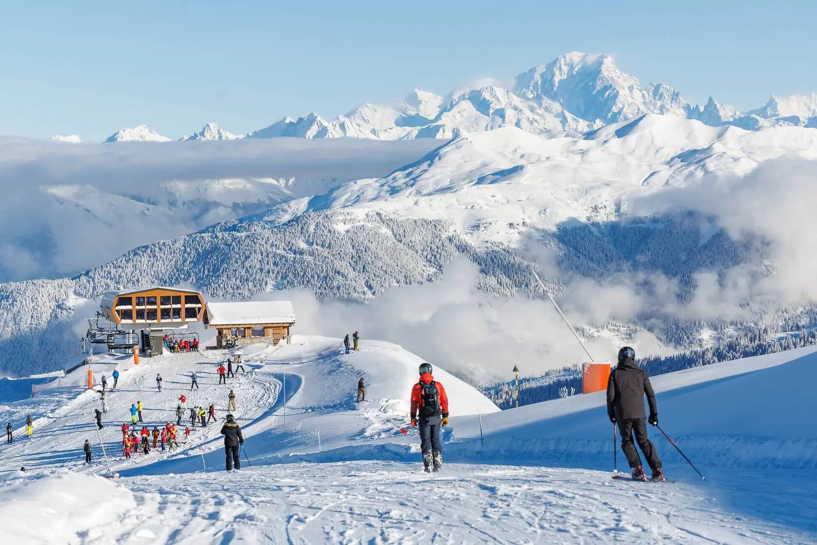Skiers on a sunny piste facing Mont Blanc above a sea of clouds, French Alps