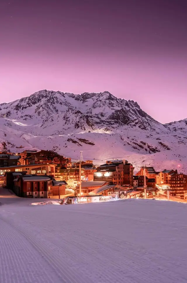 Val Thorens ski resort lit up at dusk below its snowy summits